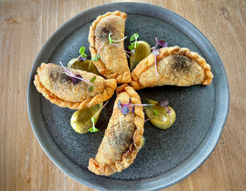 Empanada de pollo a las brasas, provolone canario y aceitunas.